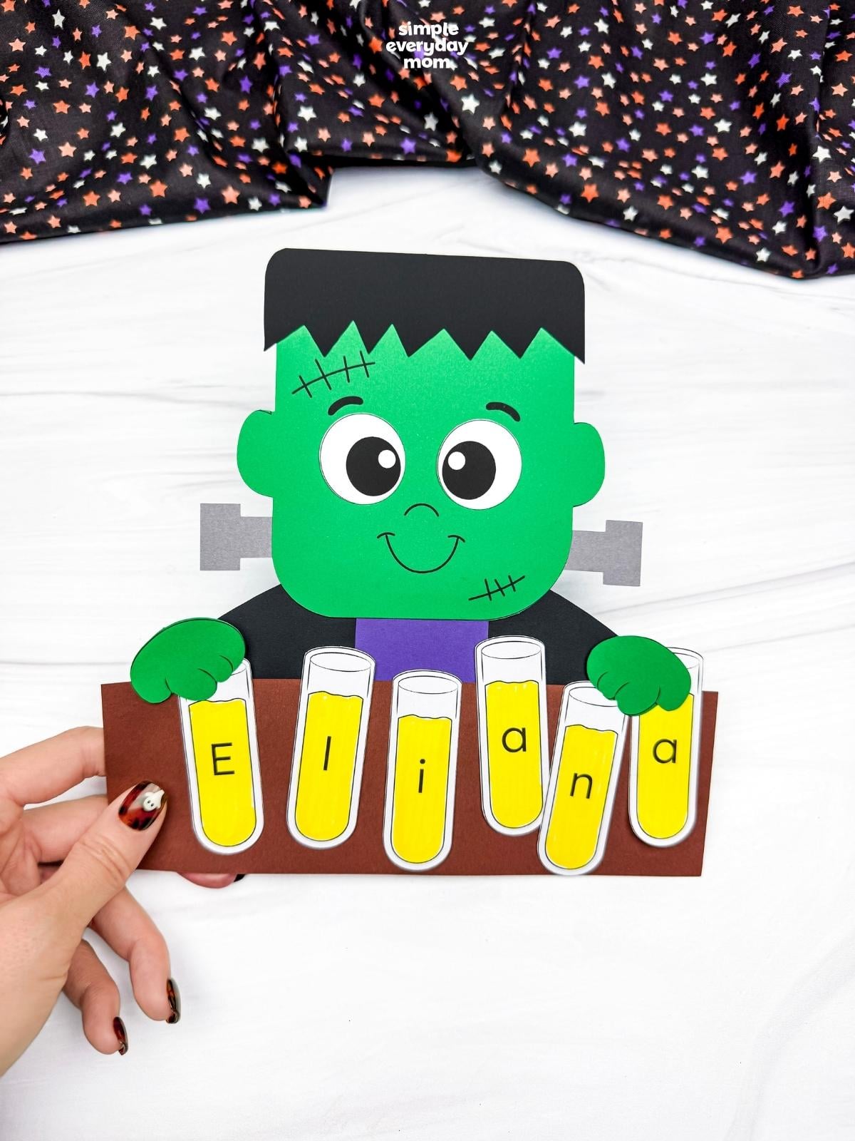 A completed craft showing a Frankenstein holding lettered test tubes that spell a child’s name.