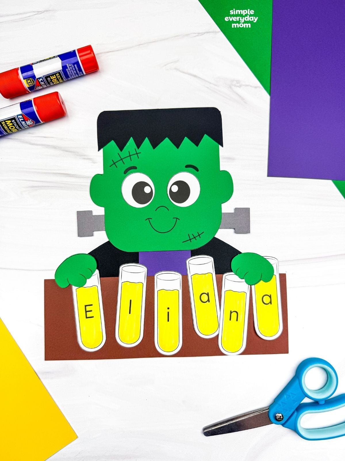 A completed craft showing a Frankenstein holding lettered test tubes that spell a child’s name.