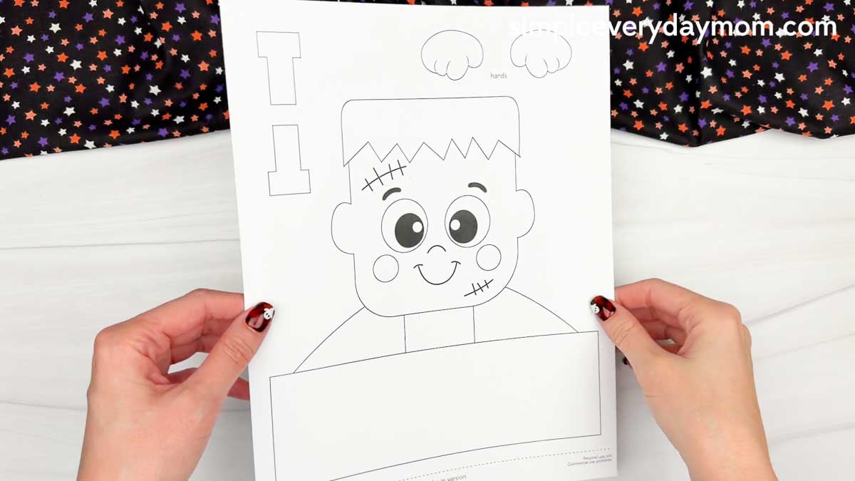 Hands holding a Frankenstein name craft printable template with the character and craft pieces ready to cut out.