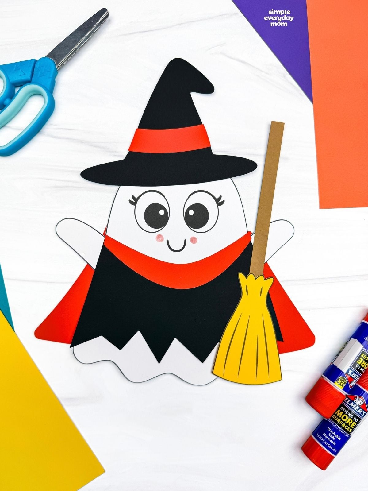 A completed craft showing a Witch Ghost Disguise with a witch hat, dress, and broom surrounded by craft supplies.