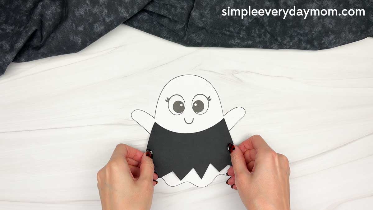 Hands placing the witch dress piece over the bottom half of the ghost template.