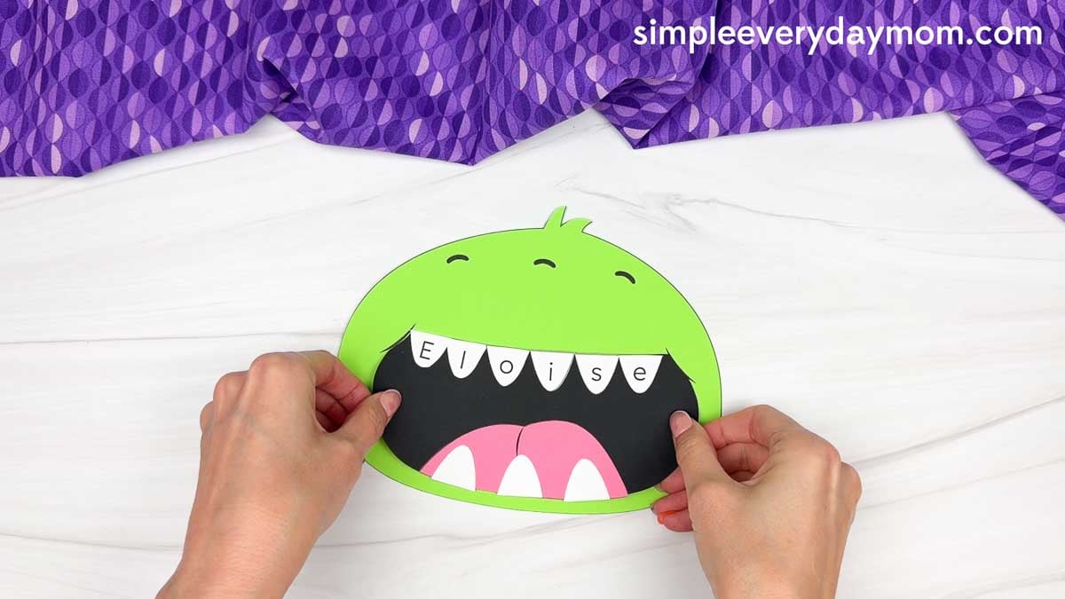 Hands gluing the monster’s mouth onto the bottom of its face.