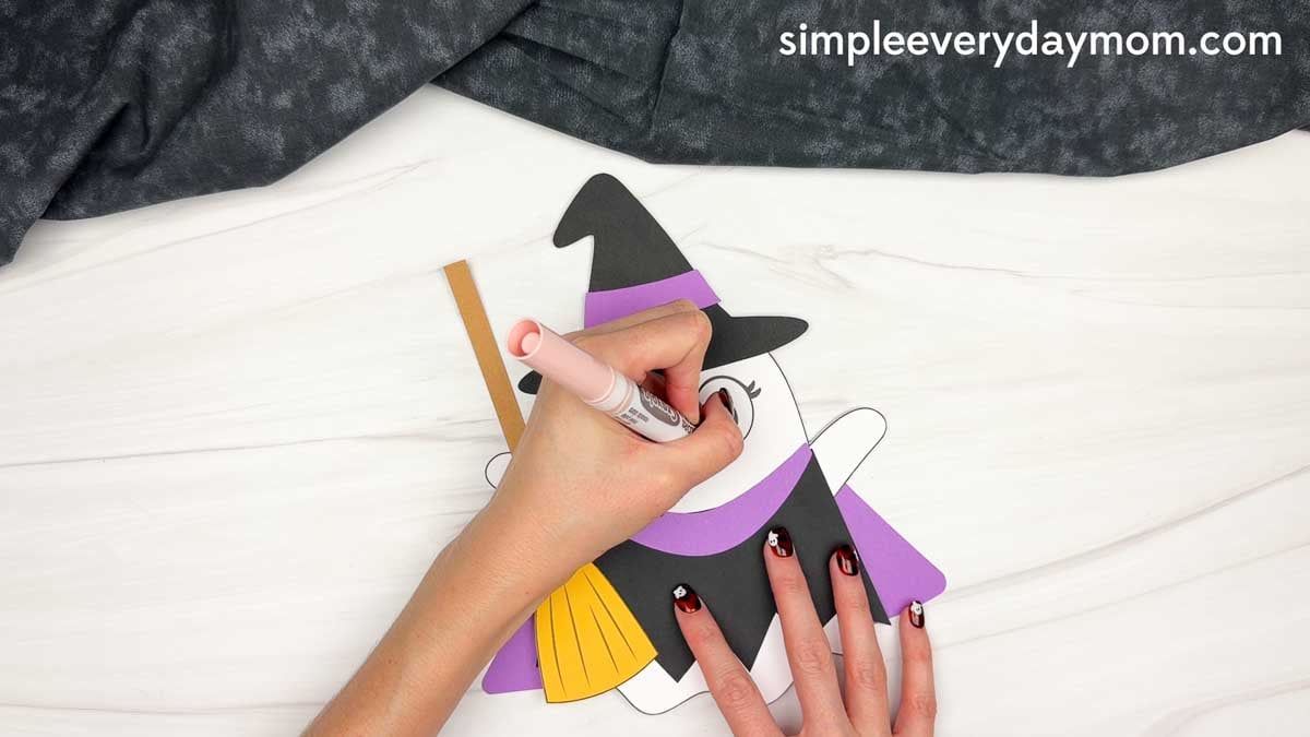 Hands using a marker to add cheeks to the Witch Ghost Disguise craft.