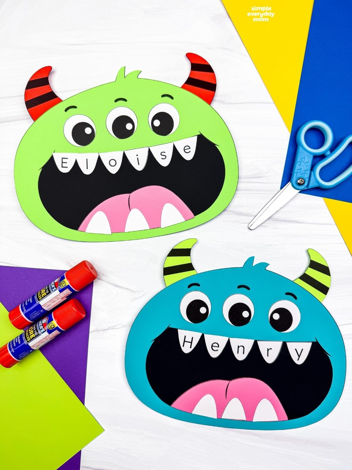 Side by side completed monster name crafts with three eyes, striped horns, and personalized letter teeth.