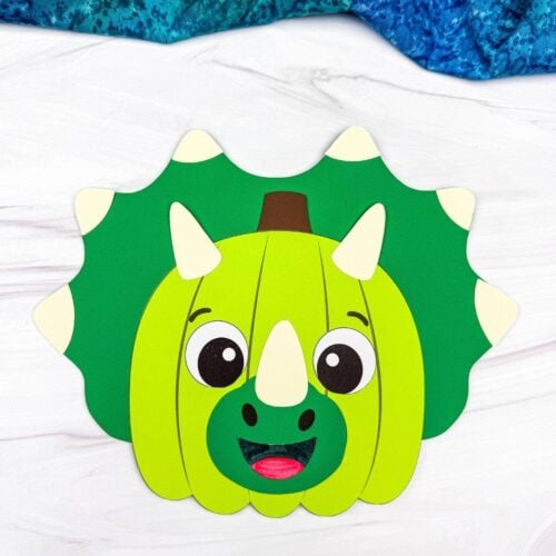 A completed craft showing a green dinosaur pumpkin disguise with horns, a smiling face, and a spiked frill.