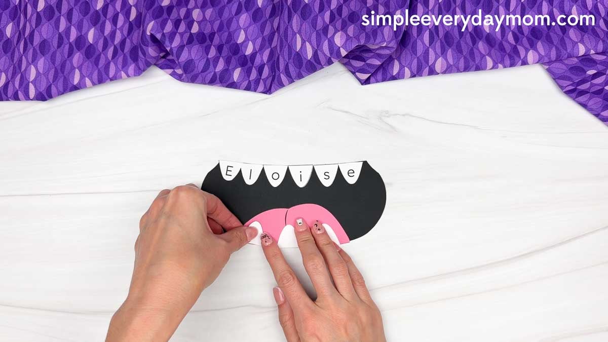 Hands gluing the bottom teeth onto the monster’s tongue.