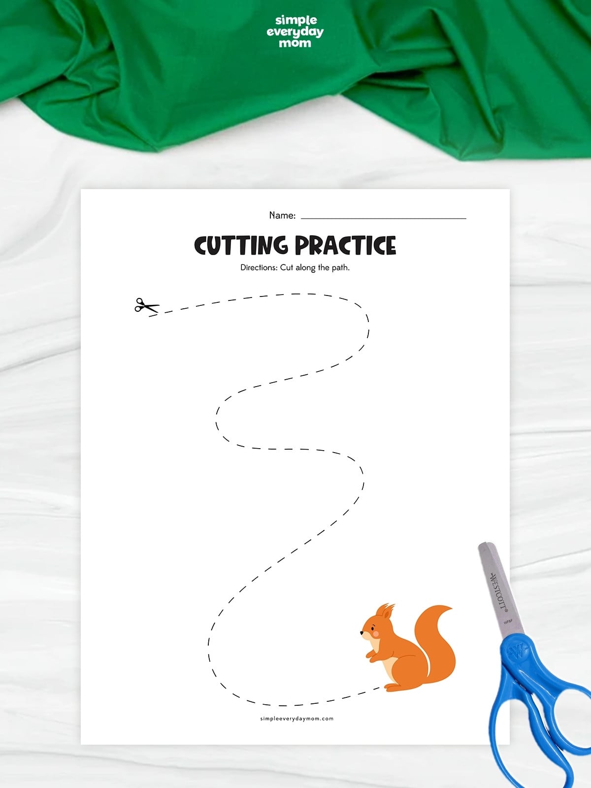 Hands cutting along a curved path toward a squirrel on a fall cutting practice worksheet.