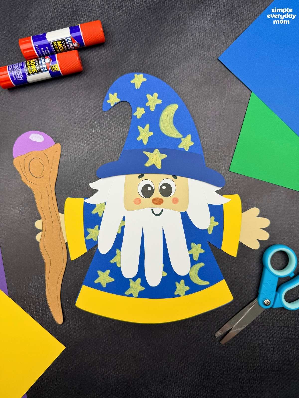 A completed Craft showing a Wizard Handprint Craft with a decorated hat, handprint beard, robe, and staff alongside craft supplies.