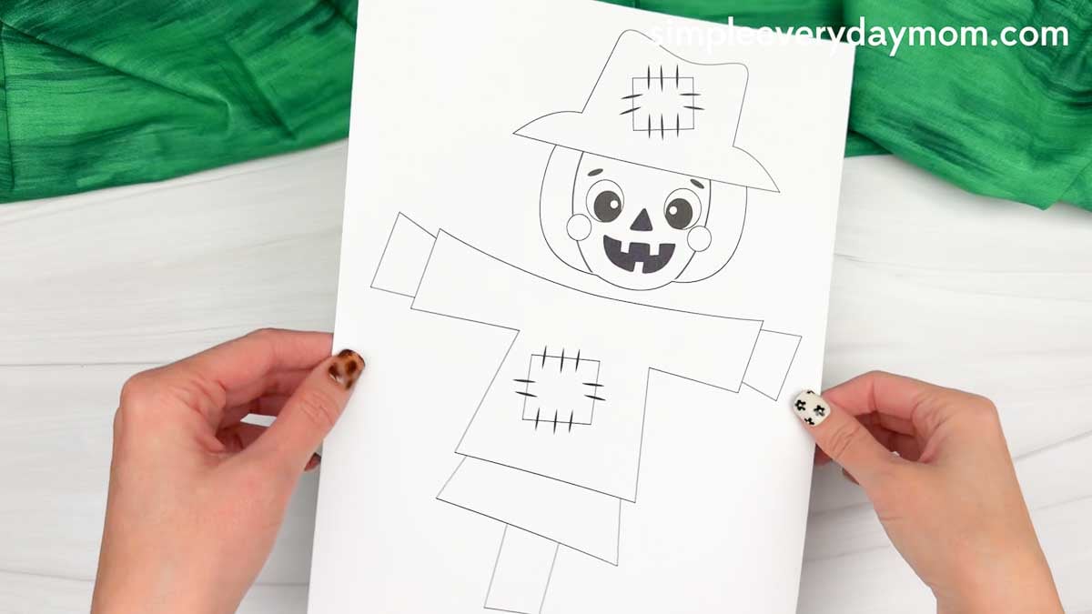 Hands holding a printable template for the Pumpkin Head Scarecrow Craft.