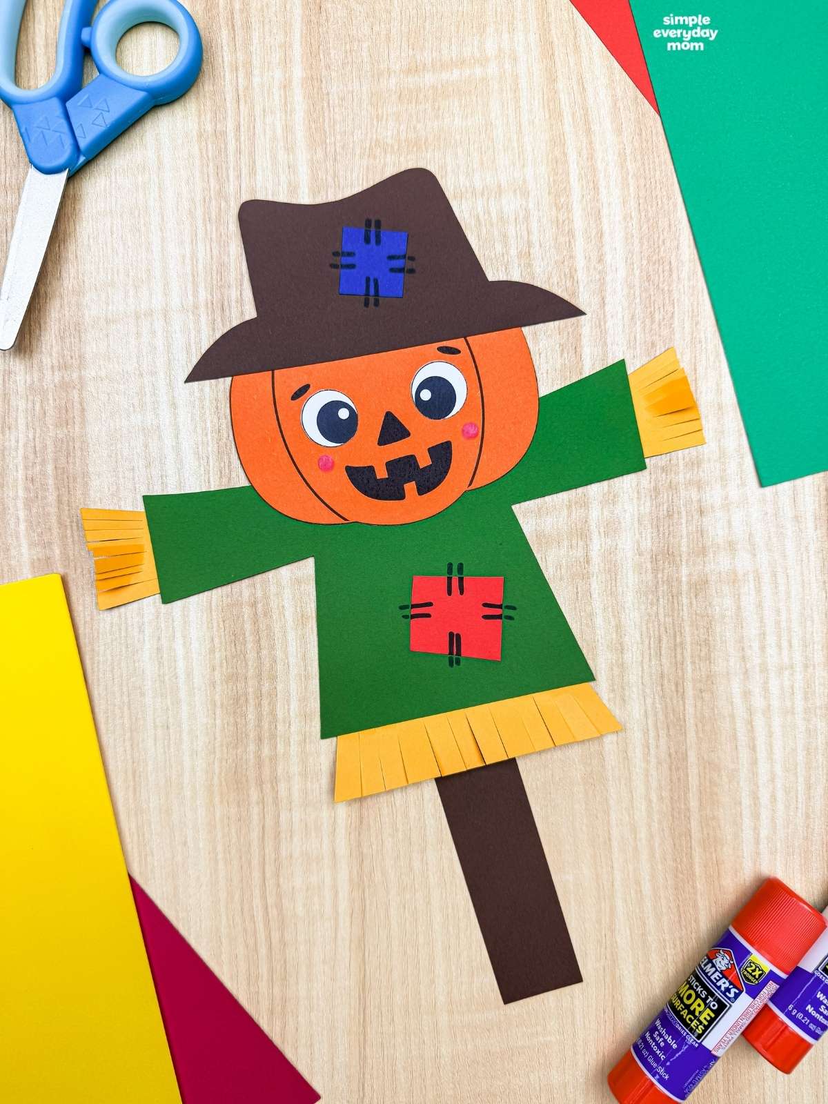 A completed Craft showing a pumpkin head scarecrow with a patched hat, shirt, straw details, and paper stick.