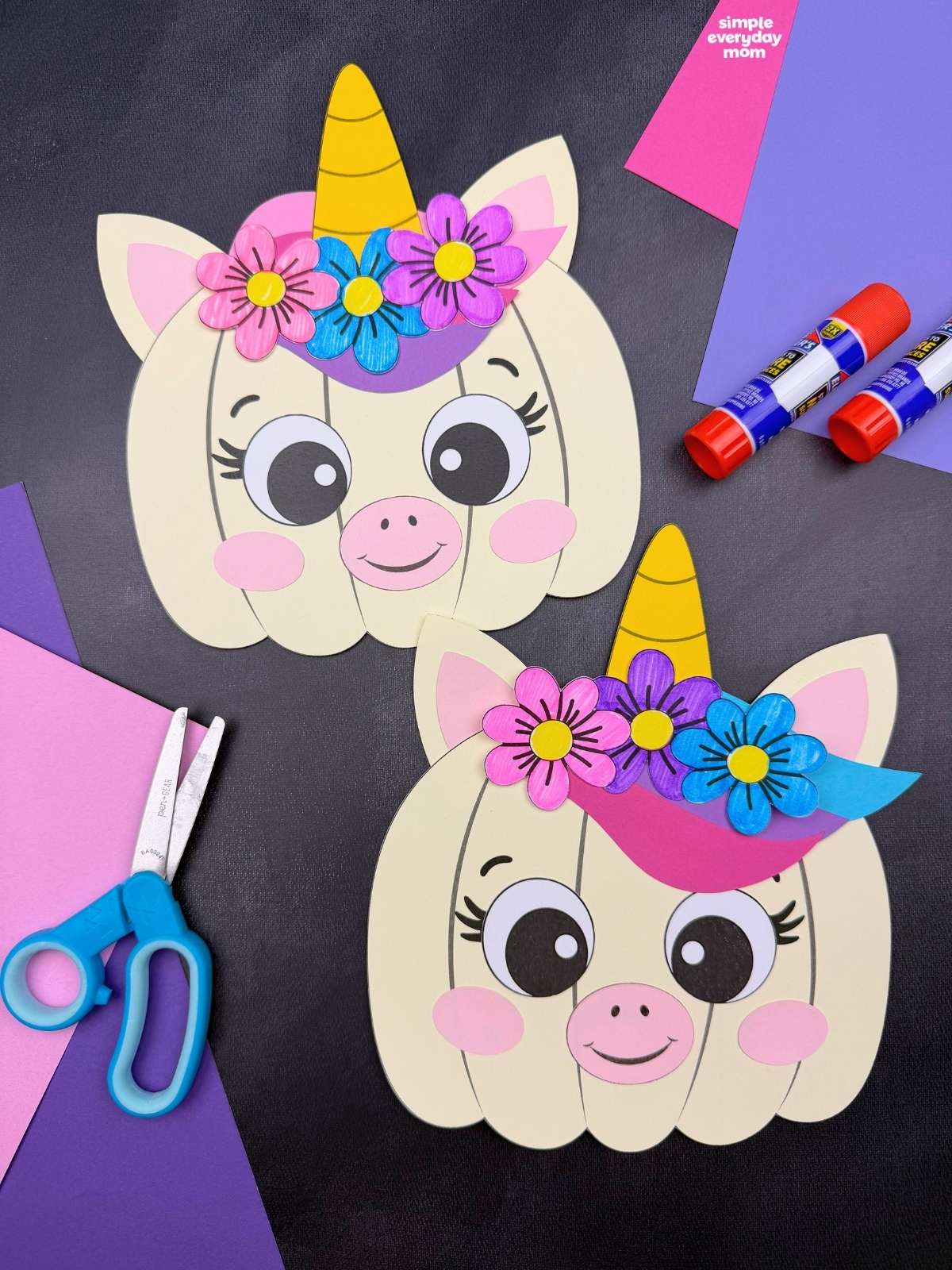 A completed craft showing two unicorn pumpkins with horns, ears, colorful flowers, and smiling faces alongside craft supplies.