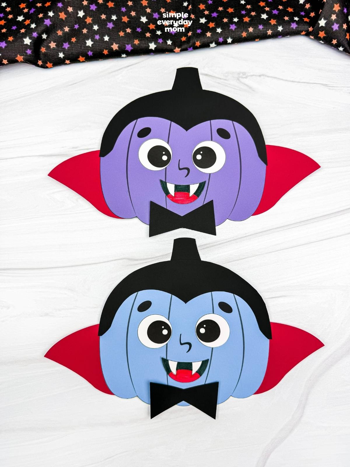 A completed craft showing two vampire pumpkin disguises with capes, fangs, bow ties, and black hair.