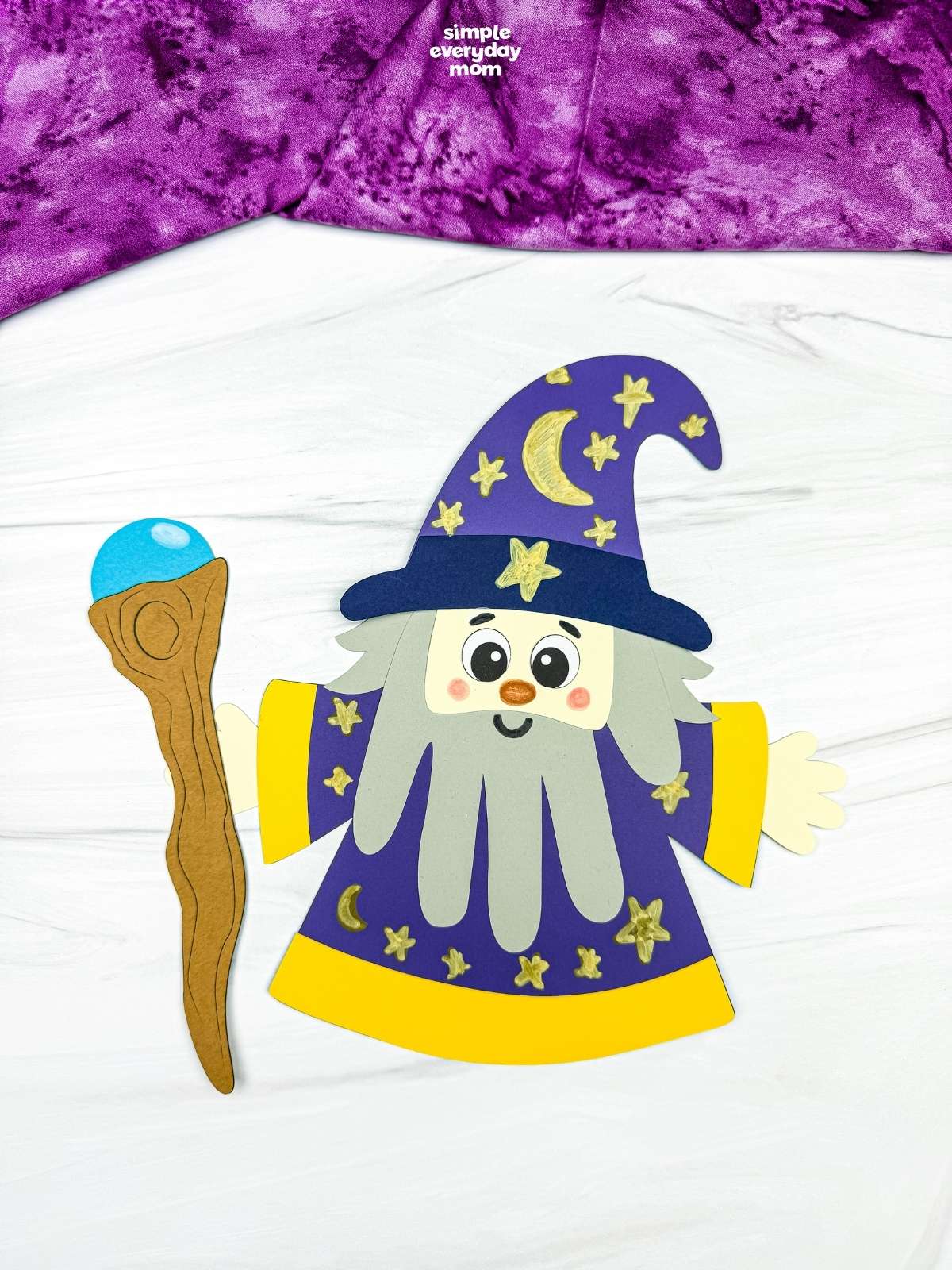 A completed Craft showing a Wizard Handprint Craft with a decorated hat, handprint beard, robe, and wizard staff.
