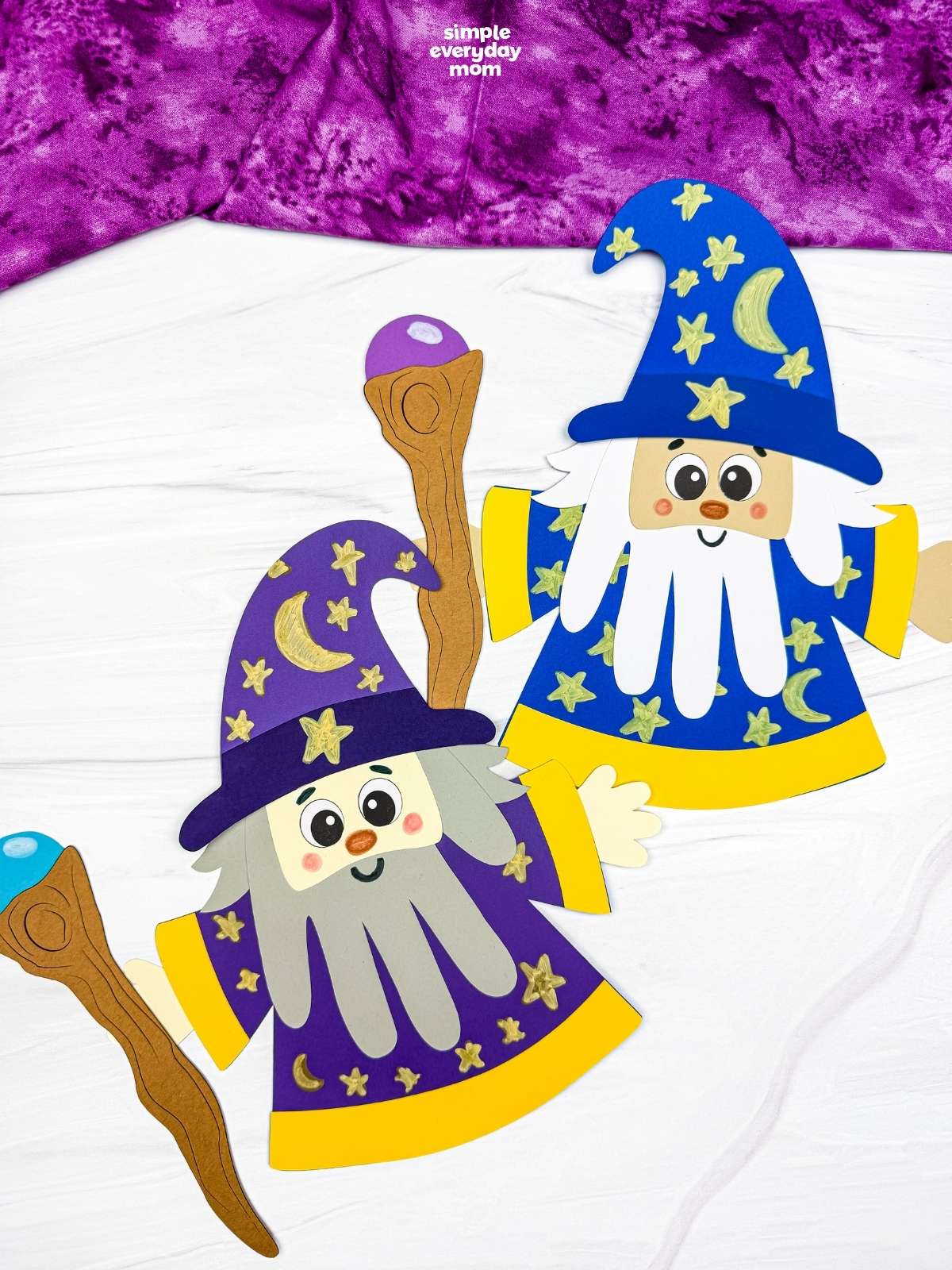 A completed Craft showing two Wizard Handprint Crafts with decorated hats, handprint beards, robes, and wizard staffs.