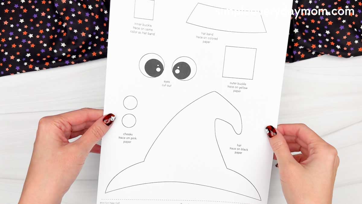 Hands holding a printable Witch Torn Paper Craft template featuring a witch hat, eyes, cheeks, hat band, and buckle pieces.