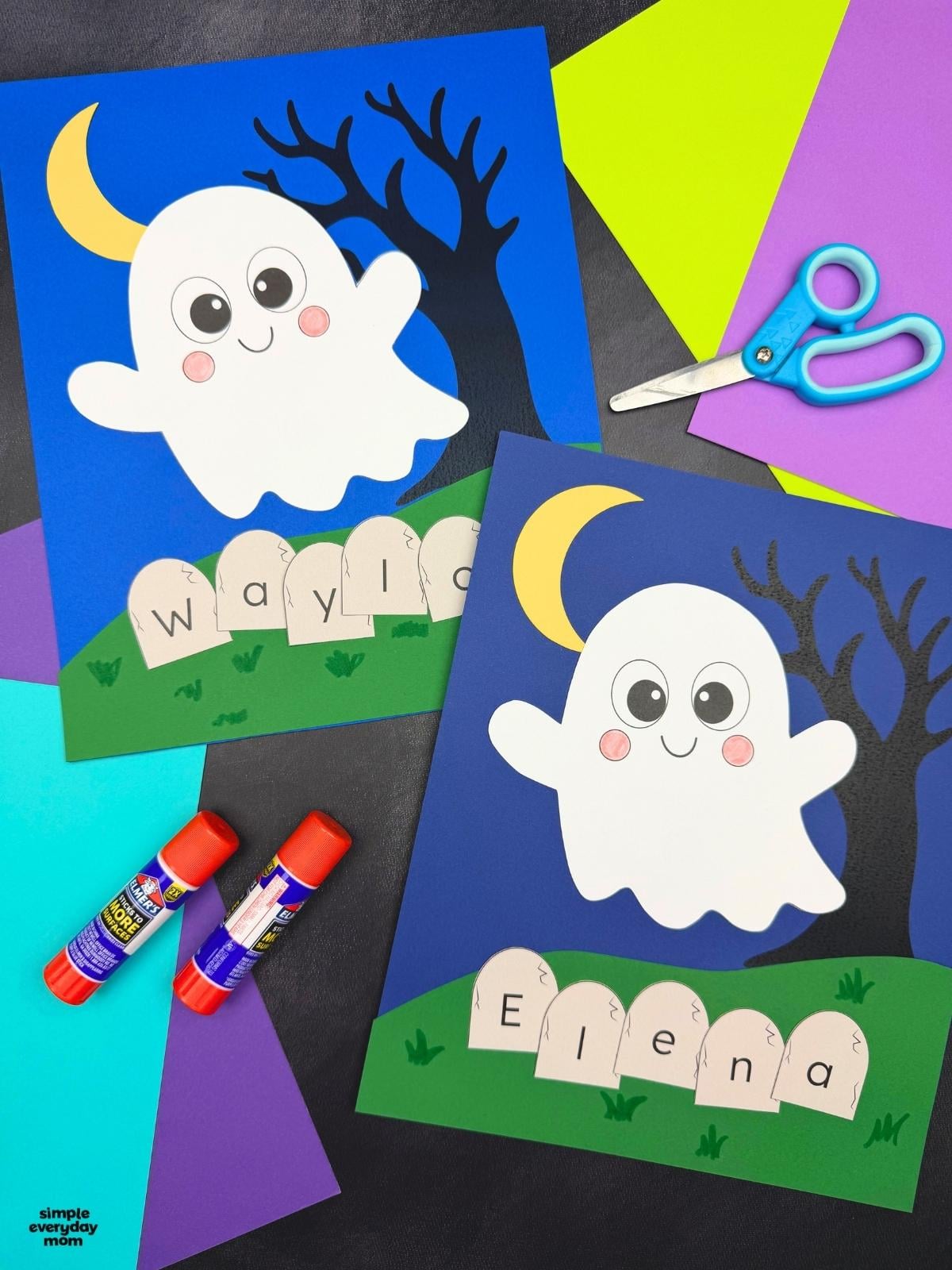 A completed Craft showing two Halloween Ghost Name Crafts with smiling ghosts, crescent moons, spooky trees, and personalized letter tombstones surrounded by colorful paper and craft supplies.