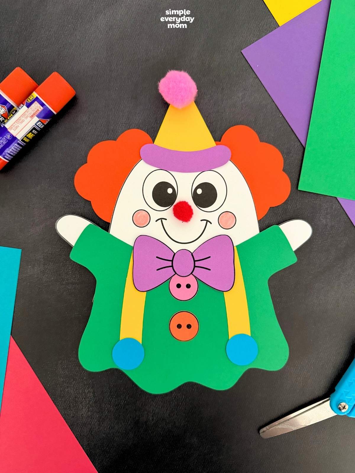 A completed craft showing a colorful clown ghost disguise with orange hair, a yellow party hat, purple bow tie, and green outfit for a fun Halloween activity for kids.