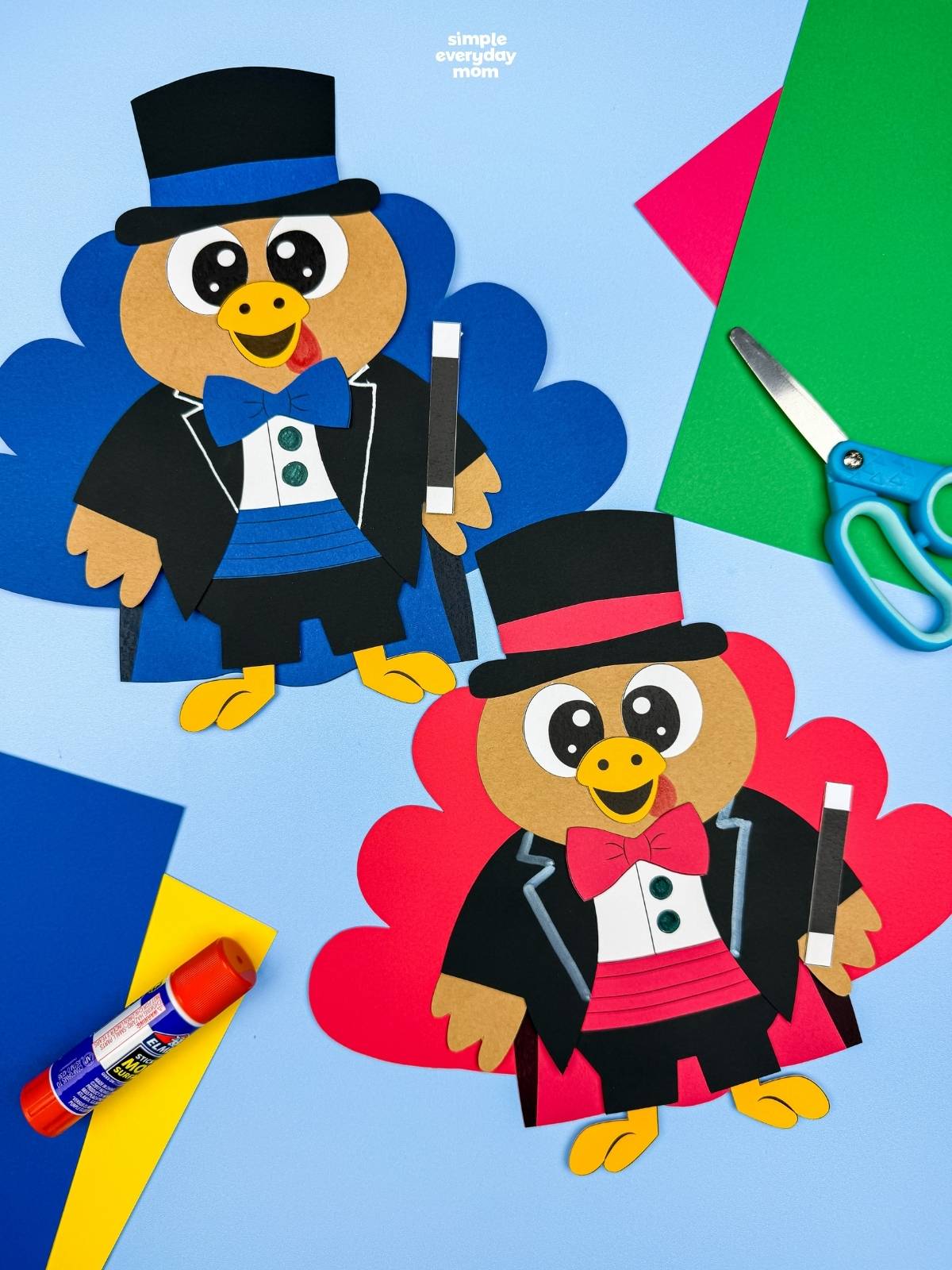 A completed craft featuring two magician turkey disguises with red and blue tail feathers, top hats, bow ties, and magic wands, surrounded by colorful craft supplies.