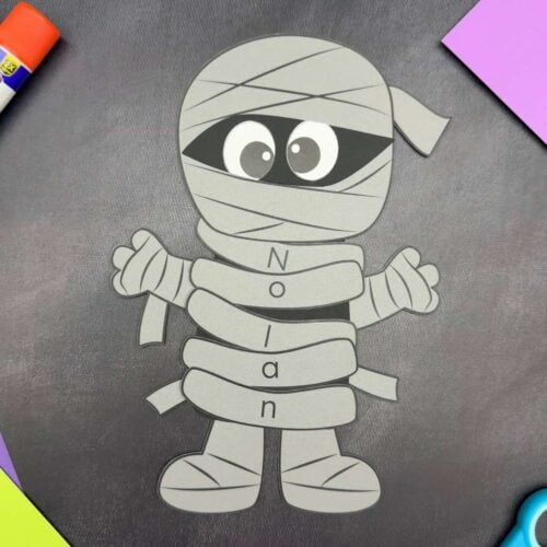 A completed craft showing a gray mummy name craft with personalized lettered wraps spelling Nolan, perfect for a Halloween name recognition activity for kids.