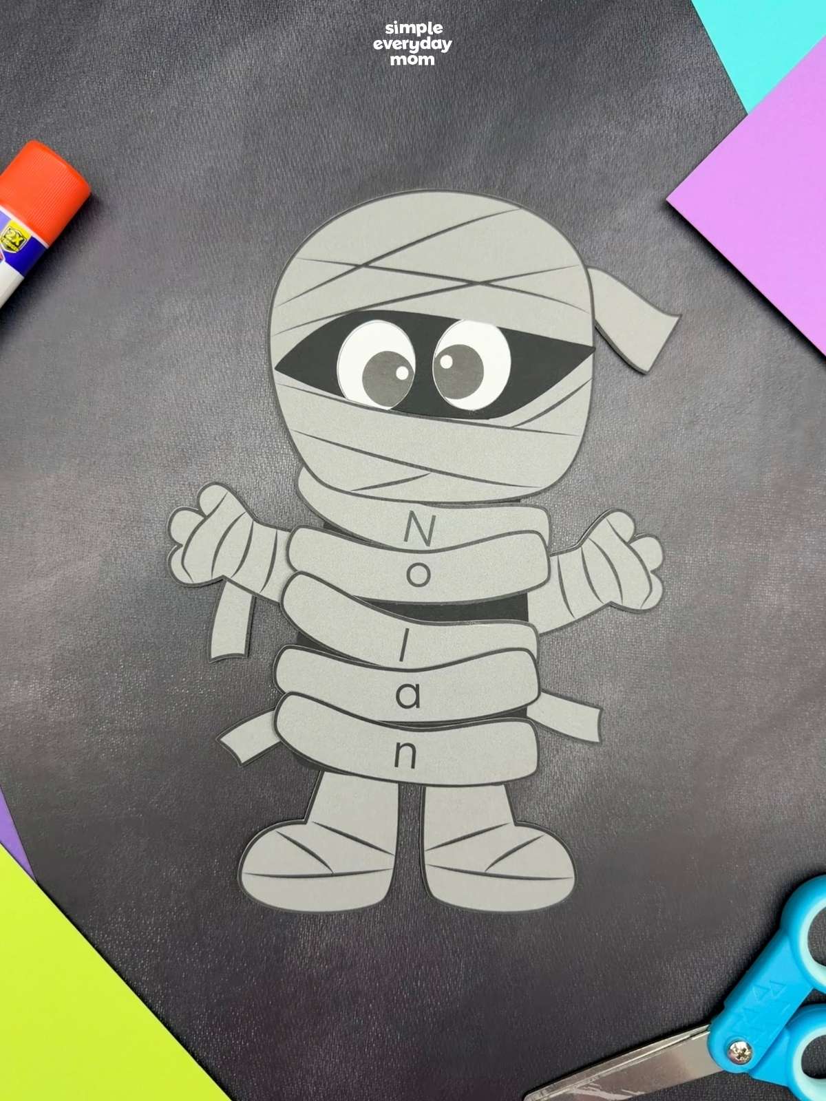 A completed craft showing a gray mummy name craft with personalized lettered wraps spelling Nolan, perfect for a Halloween name recognition activity for kids.
