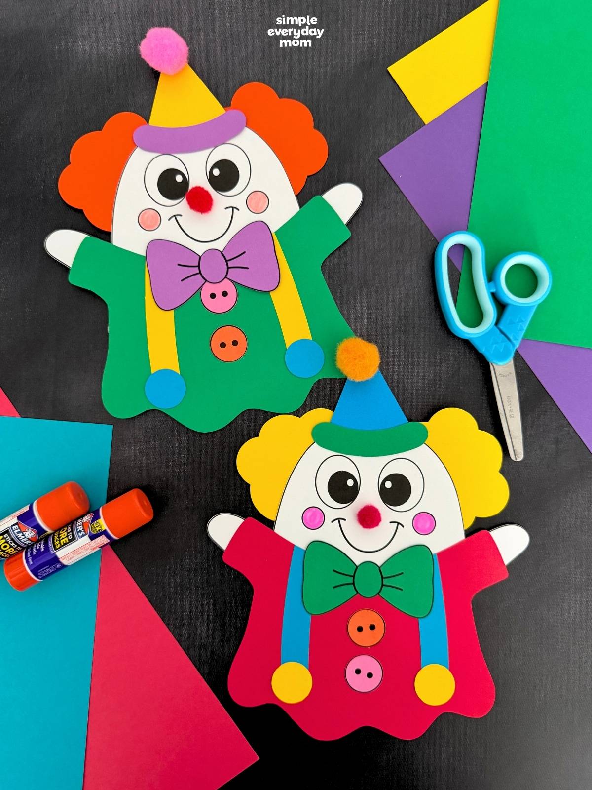 A completed craft display of two colorful clown ghost disguises with party hats, bow ties, pom-pom noses, and bright outfits for a fun Halloween paper craft.