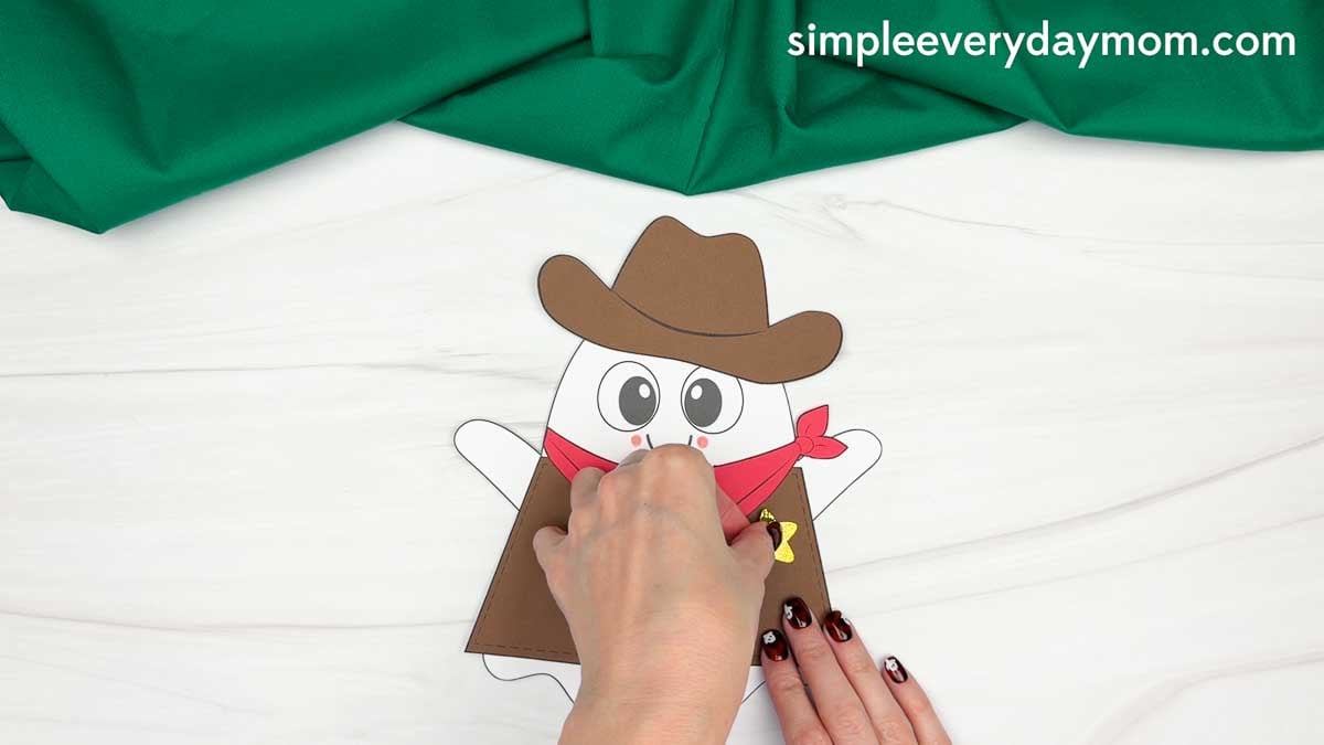 Hands gluing the star badge onto the cowboy vest for the Cowboy Ghost Disguise Craft.