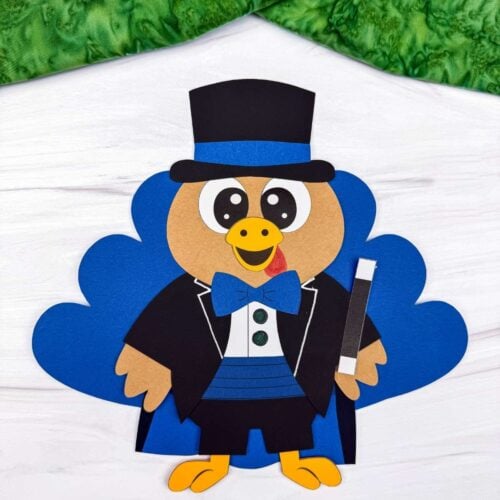 A completed craft of a magician turkey disguise featuring blue tail feathers, a black top hat, blue bow tie, black jacket, and magic wand.