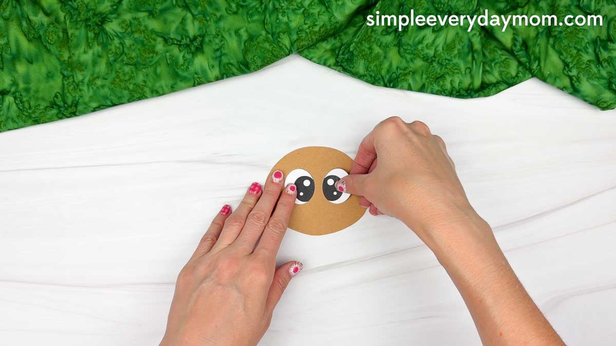 Hands gluing the eyes onto the brown turkey head for the Magician Turkey Disguise Craft.