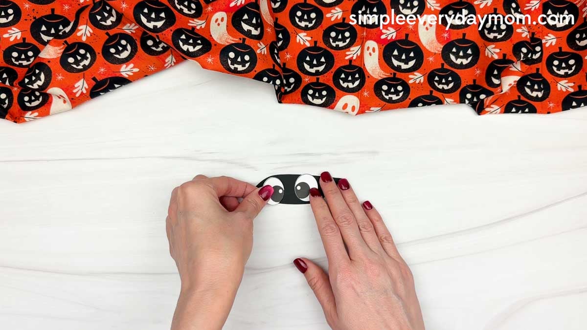 Hands arranging the eyes piece for a mummy name craft Halloween activity for kids.