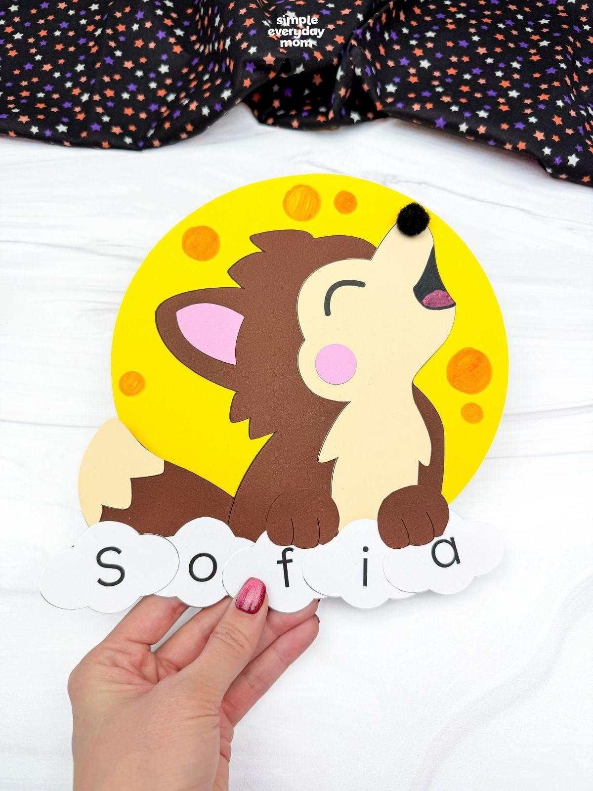 Hands holding a completed werewolf name craft featuring a howling wolf, yellow full moon, and lettered pieces spelling Sofia for a fun Halloween activity.